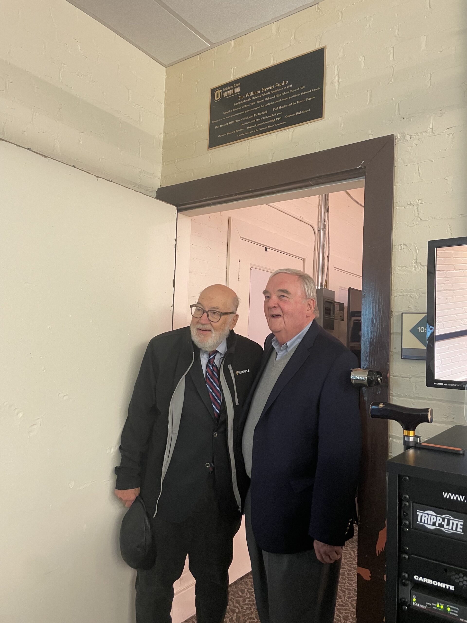 Men standing under plaque dedication 